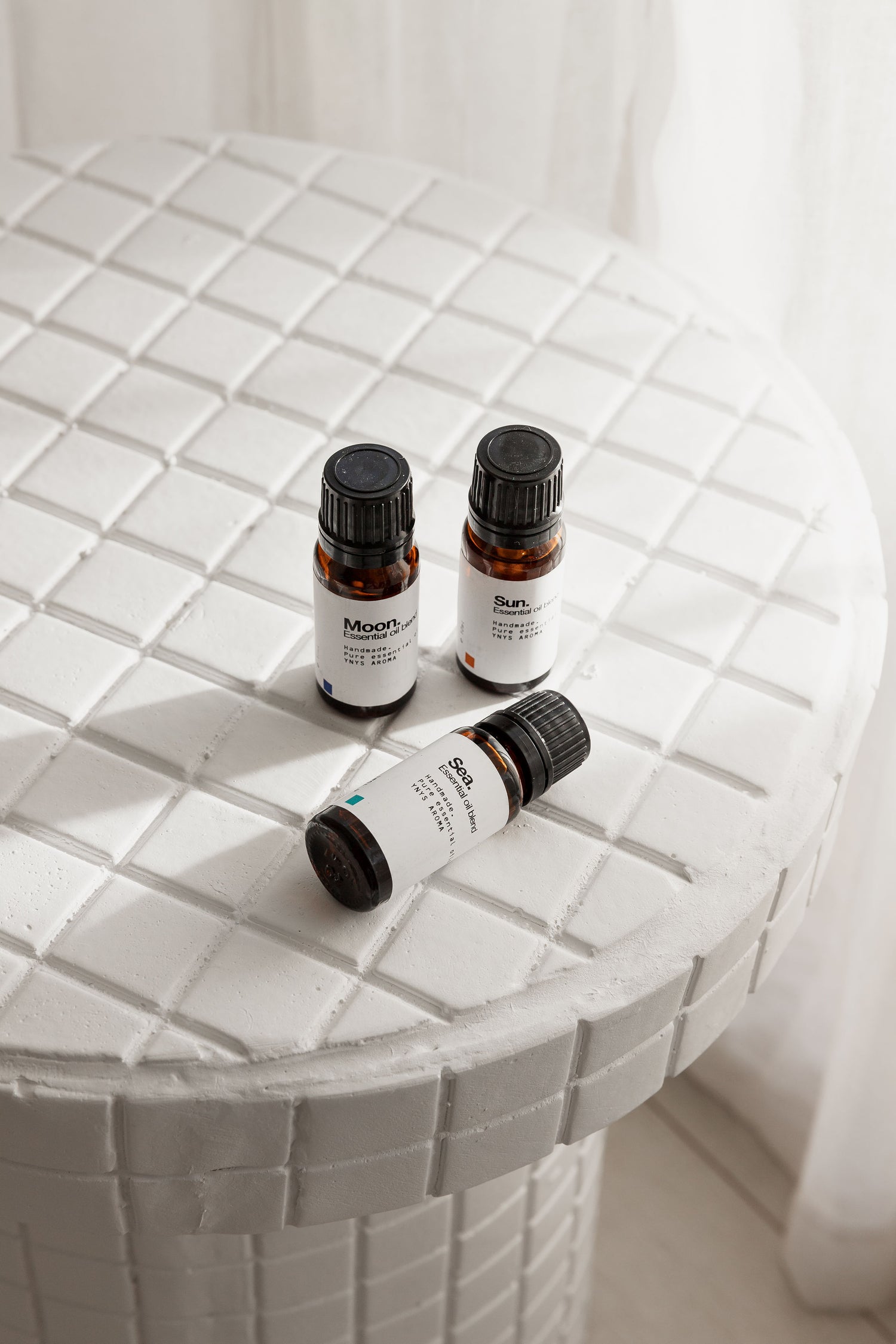 three bottles of essential oils sitting on a white ceramic table.