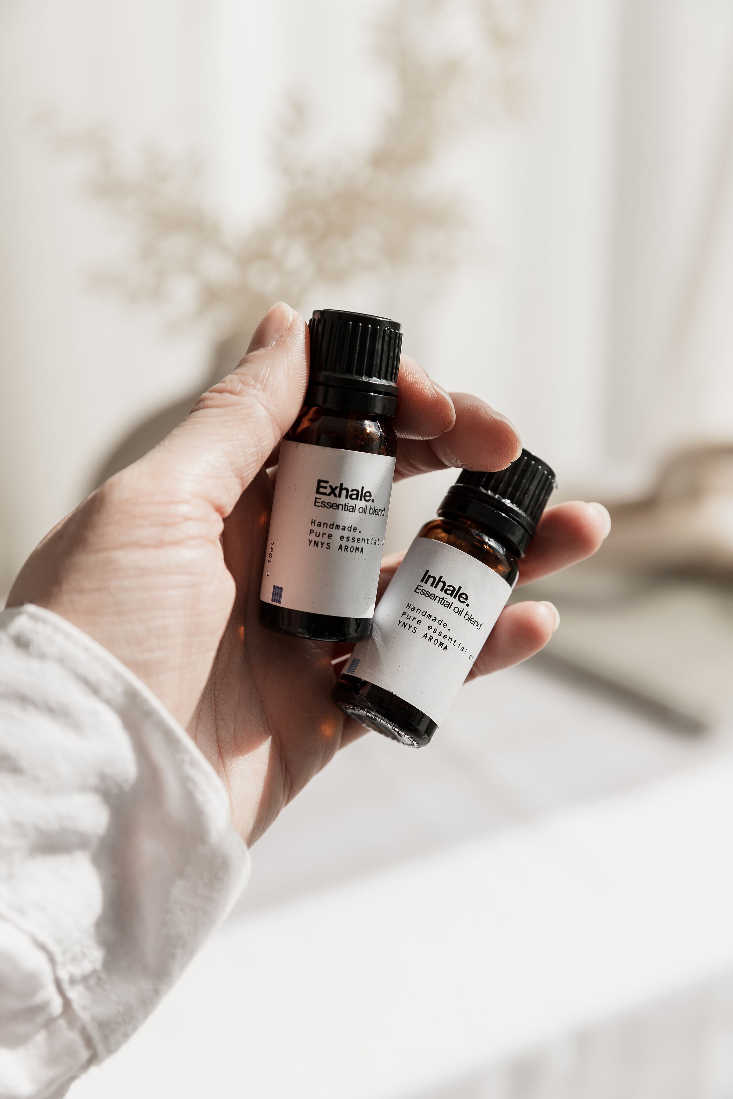 three bottles of essential oils sitting on a white ceramic table.